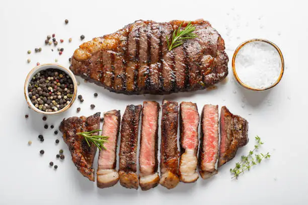 Two grilled marbled beef steaks striploin with spices isolated on white background, top view.