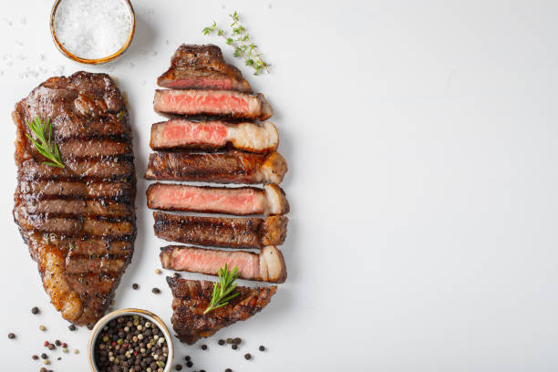 istock Two grilled marbled beef steaks striploin with spices isolated on white background, top view with copy space 1050993764