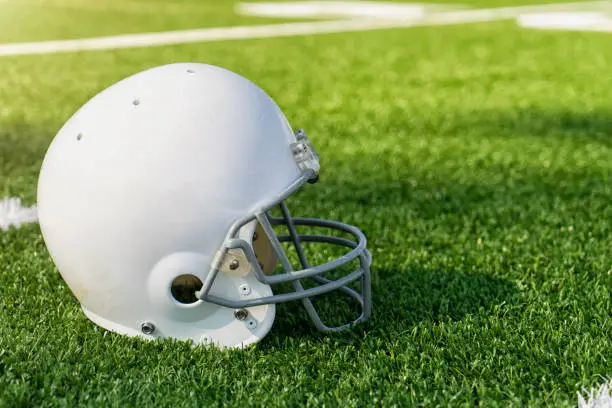 An American football helmet on a professional football field with helmet and copy space.