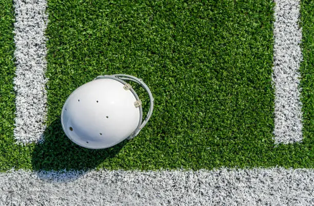 An American football helmet on a professional football field with helmet and copy space.