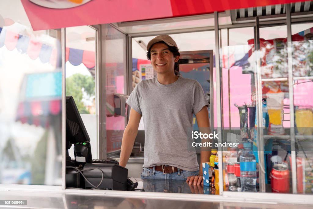 Man selling food in a truck at an amusement park Portrait of a happy man selling food in a truck at an amusement park - lifestyle concepts Traveling Carnival Stock Photo