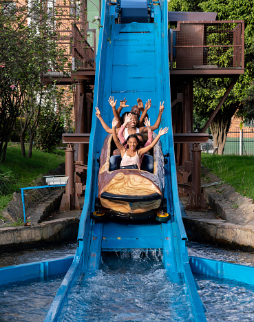 Black family having fun and getting wet in a water ride at an amusement park - lifestyle concepts