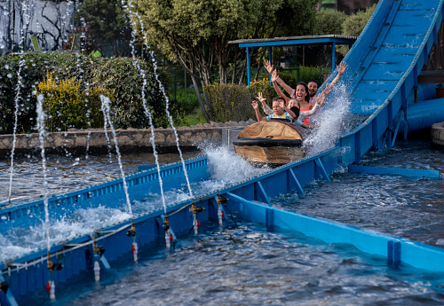 Happy family having fun in an amusement park riding on a fun water ride - lifestyle concepts