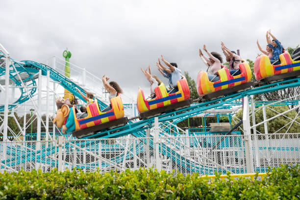 счастливые люди едут на американских горках в парке развлечений - rollercoaster carnival amusement park ride screaming стоковые фото и изображения