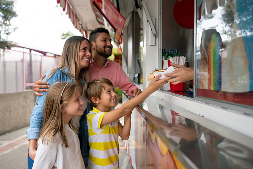 Portrait of a happy family buying food at an amusement park - lifestyle concepts