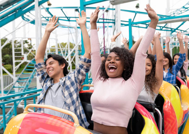 Happy group of people having fun in a rollercoaster at an amusement park Happy group of people having fun in an amusement park riding on a rollercoaster with arms up and screaming - lifestyle concepts rollercoaster photos stock pictures, royalty-free photos & images