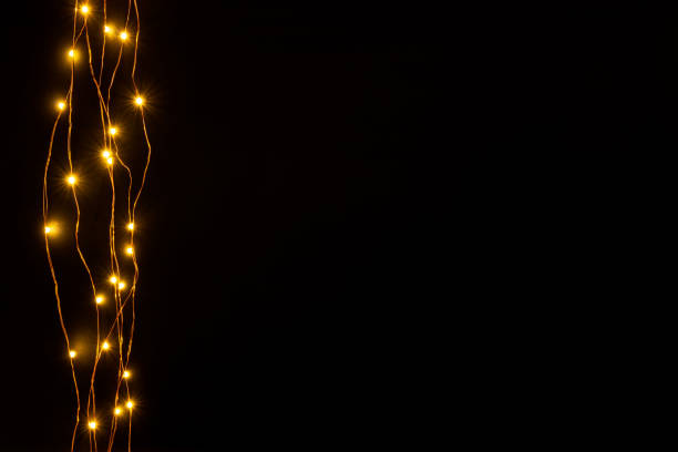 Christmas lights garland border over black background. Flat lay, copy space.