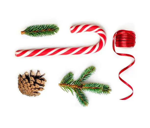 Photo of Christmas composition  with fir tree branches, red ribbon and Christmas Candy cane  on white background.  Flat lay. Top view