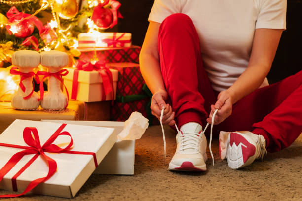 femme en pyjama lie les lacets de chaussures de sport. cadeau de noël. cadeau d’anniversaire. - holiday healthy lifestyle weight christmas photos et images de collection