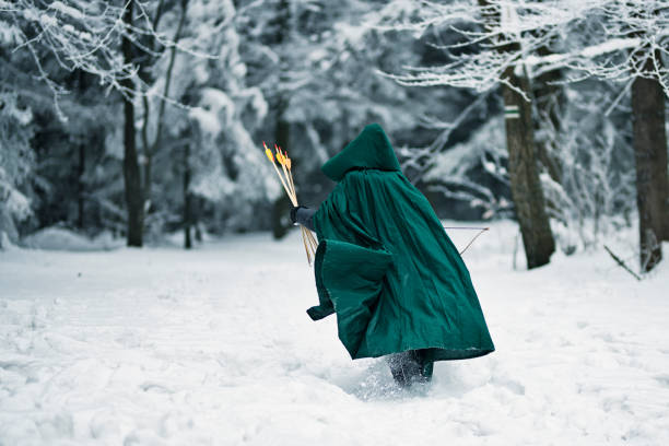 Little boy aged 8 playing ranger in winter forest. The boy wearing a green coat and is running in snow.