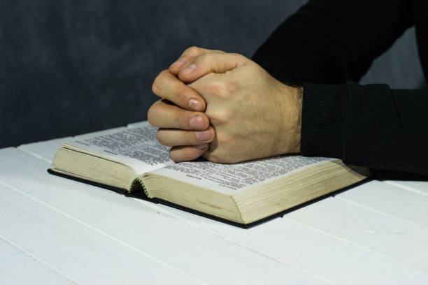 istock Young man sitting at a table reading the Holy Bible 1051058224