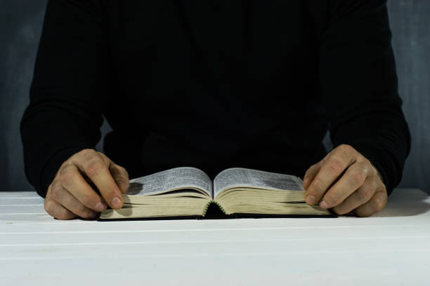 istock Young man sitting at a table reading the Holy Bible 1051062588
