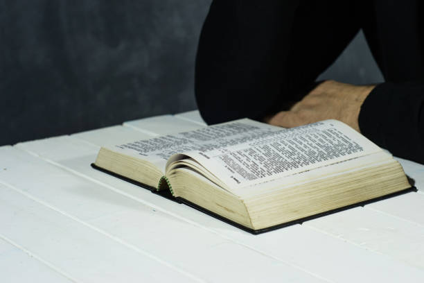 istock Young man sitting at a table reading the Holy Bible 1051065388