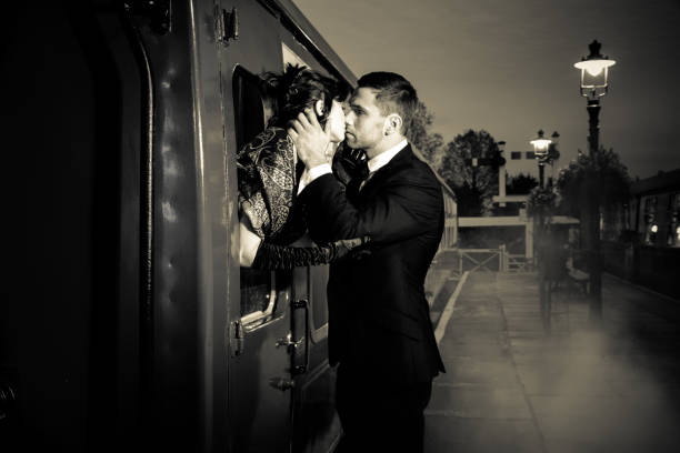 coppia vintage che abbraccia e bacia sulla banchina della stazione ferroviaria mentre il treno sta per partire - depart foto e immagini stock