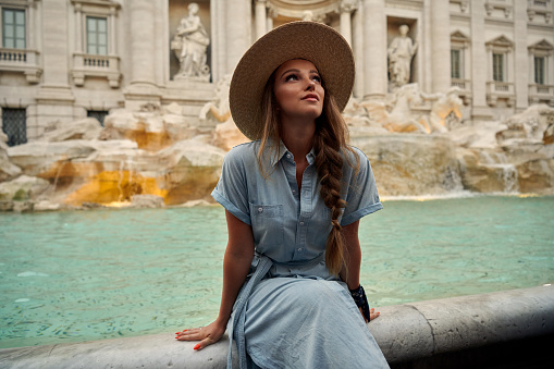 Italian vacations series. Young woman makes a wish at the Trevi Fountain