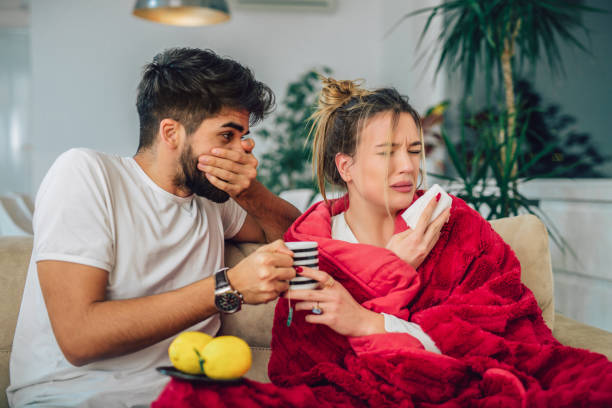 istock Handsome man taking care of his sick girlfriend lying on the sofa 1051075082