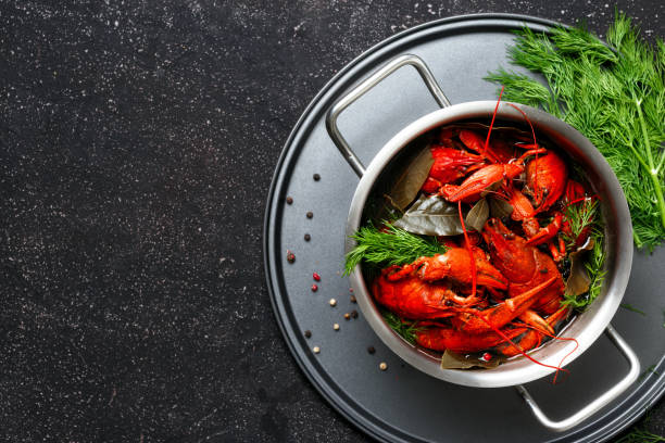 istock Boiled crawfish dill bay leaf saucepan black background top view 1051078180