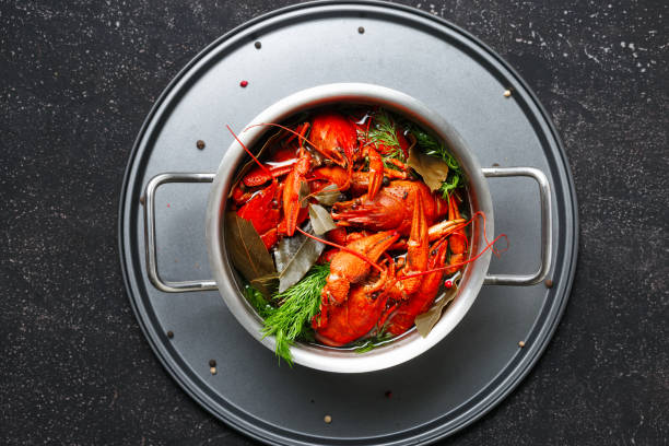istock Boiled crawfish dill bay leaf saucepan black background top view 1051078196