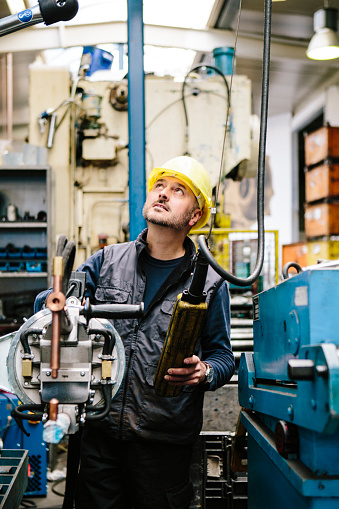 technician transports a welding point pliers with a crane in a workshop