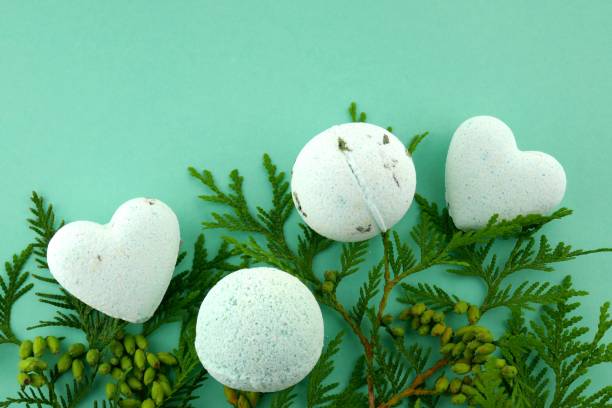 istock thuja bath bombs.Organic body cosmetics with Thuja extract.bath bombs round and heart form and twigs of fresh thuja on green background. 1051086276