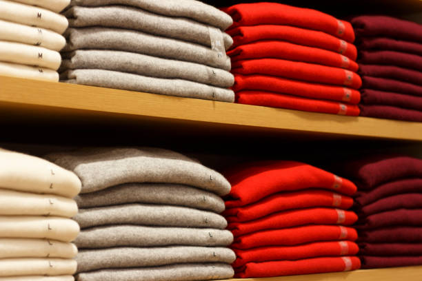 Colorful clothes background .Various color sweaters perfectly folded on a shelf in the shop.