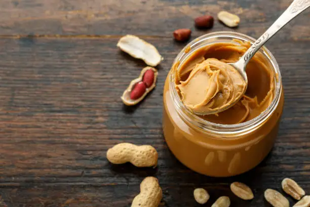 Photo of peanut paste in an open jar and peanuts