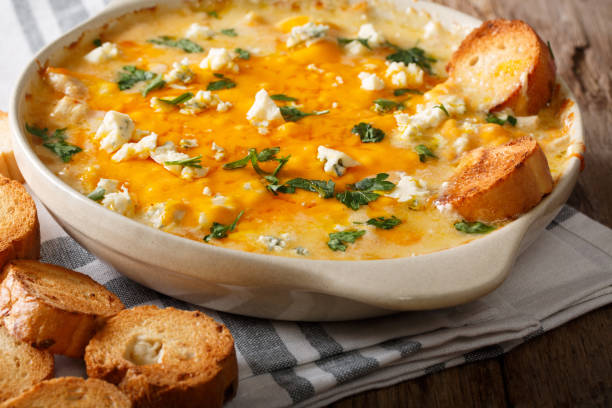 Homemade hot buffalo chicken dip with crostini close up in baking dish. horizontal Homemade hot buffalo chicken dip with crostini close up in baking dish on the table. horizontal dipping sauce stock pictures, royalty-free photos & images