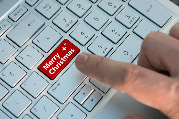 istock Computer notebook keyboard with merry Christmas key - technology background. A male finger presses a color button on a gray silver keyboard of a modern laptop 1051095956