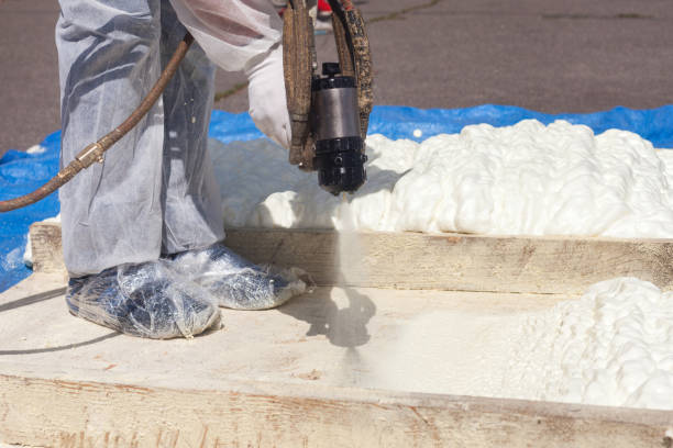 Technician spraying foam insulation using Plural Component Spray Gun. Spraying polyurethane foam for roof Technician dressed in a protective white uniform spraying foam insulation using Plural Component Spray Gun. Spraying polyurethane foam for roof and energy saving spray insulation stock pictures, royalty-free photos & images