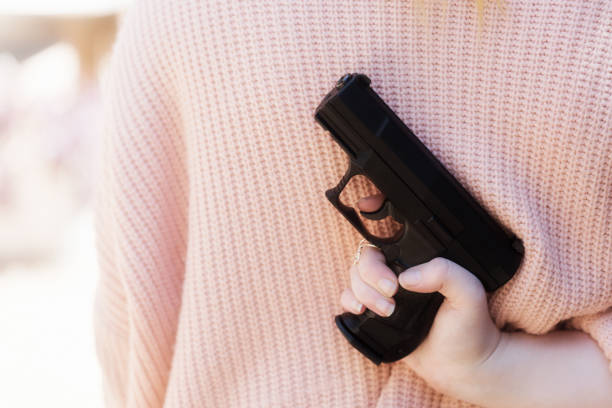 istock Female hand holds pistol behind her back 1051106706
