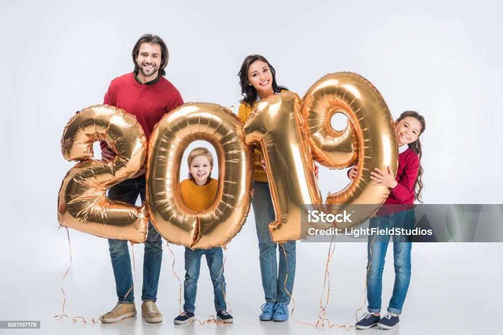Familia feliz celebración de oro globos 2019 signo para el año nuevo y mirando a cámara aislada en blanco - Foto de stock de 2019 libre de derechos