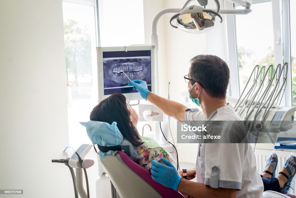 Medico dentista che mostra i denti del paziente ai raggi X - Foto stock royalty-free di Dentista