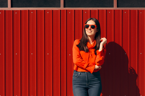 Casual woman wearing a red hoodie and shades in outdoor portrait