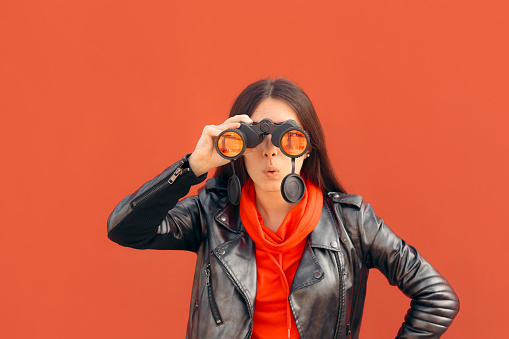 Cool woman wearing leather jacket using binocular device