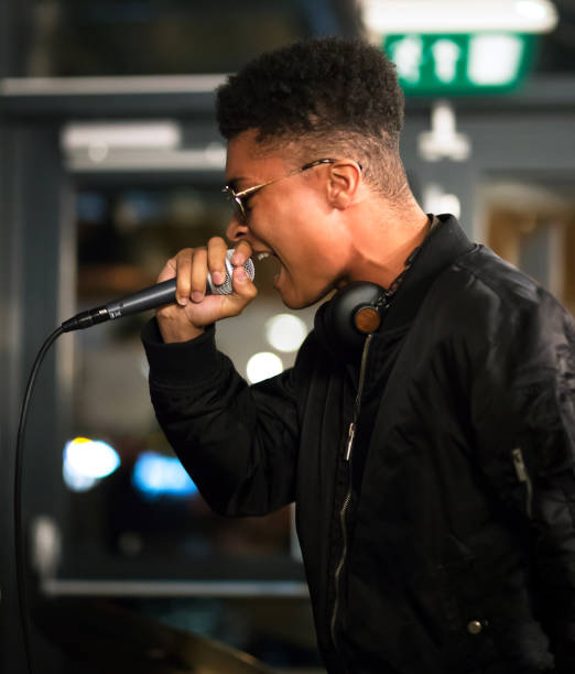 Black rapper performing with microphone. Side profile. stock photo