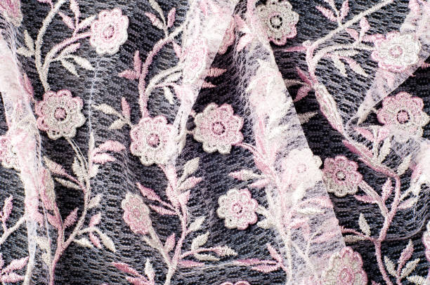 istock Texture, background, pattern. Pink lace decorated with flowers on a black background. Lace decorated with a pattern and decorative rose on a black background. 1051135956