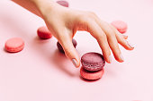 Beautiful female hands with trendy manicure holding pink macaroon cake.