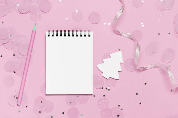 istock Empty note book - christmas and new year mock up template with pink confetti on pink background 1051139876