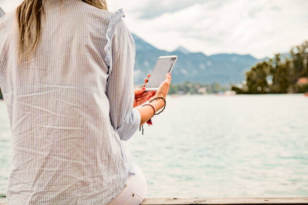 istock Girl on a wooden pier using smartphone. 1051140460