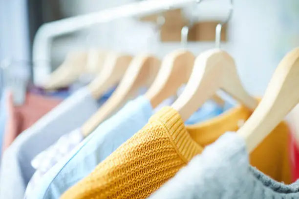 Row of wooden hangers with collection of casual clothes in studio of modern fashion and design