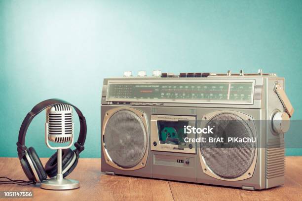 Retro outdated portable stereo boombox radio cassette recorder from circa  late 70s with aged headphones front gradient black wall background.  Listening music concept. Vintage old style filtered photo Stock Photo