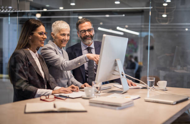 Happy business colleagues using desktop PC at corporate office.