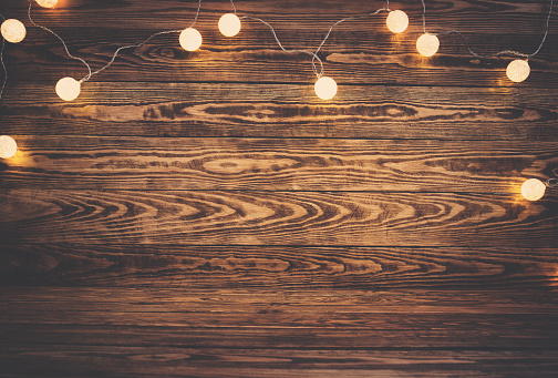 Old wooden planks with christmas decoration. Brown background with lightbulbs