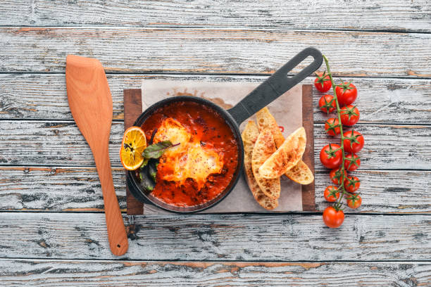 Eggs with tomatoes and toast bread in a frying pan. Shakshuka Top view. Free space for your text. On a wooden background.