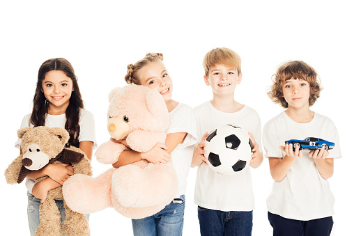 smiling children holding toys and looking at camera isolated on white