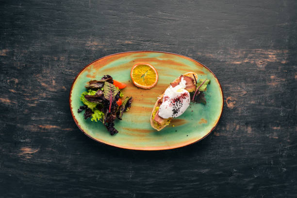 istock Sandwich with avocado, bacon and poached egg. Top view. Free space for your text. On a wooden background. 1051172116