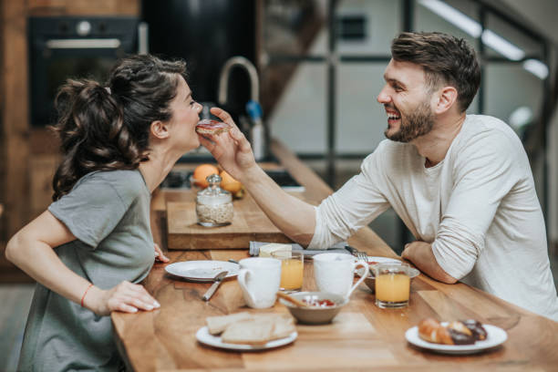 istock Happy man feeding his girlfriend during breakfast time at home. 1051176010