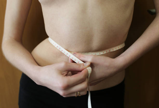 Slim girl is measuring her waist with a centimetre tape measure at home. Fit sport healthy photo. Successful diet. Slim girl is measuring her waist with a centimetre tape measure at home. Fit sport healthy photo. Successful diet. centimetre stock pictures, royalty-free photos & images