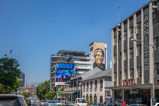 Braamfontein suburb in Johannesburg with mural of Nelson Mandela and traffic near the Neighbourhood Market.\nJohannesburg, also known as Jozi, Jo'burg or eGoli, \