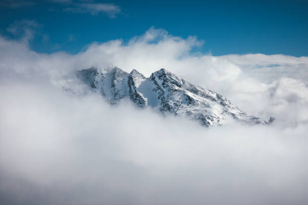 Mountain Peak In Clouds Majestic snowcapped mountain in France (Val Thorens). View from Cime Caron (3200m). Surrounding stock pictures, royalty-free photos & images